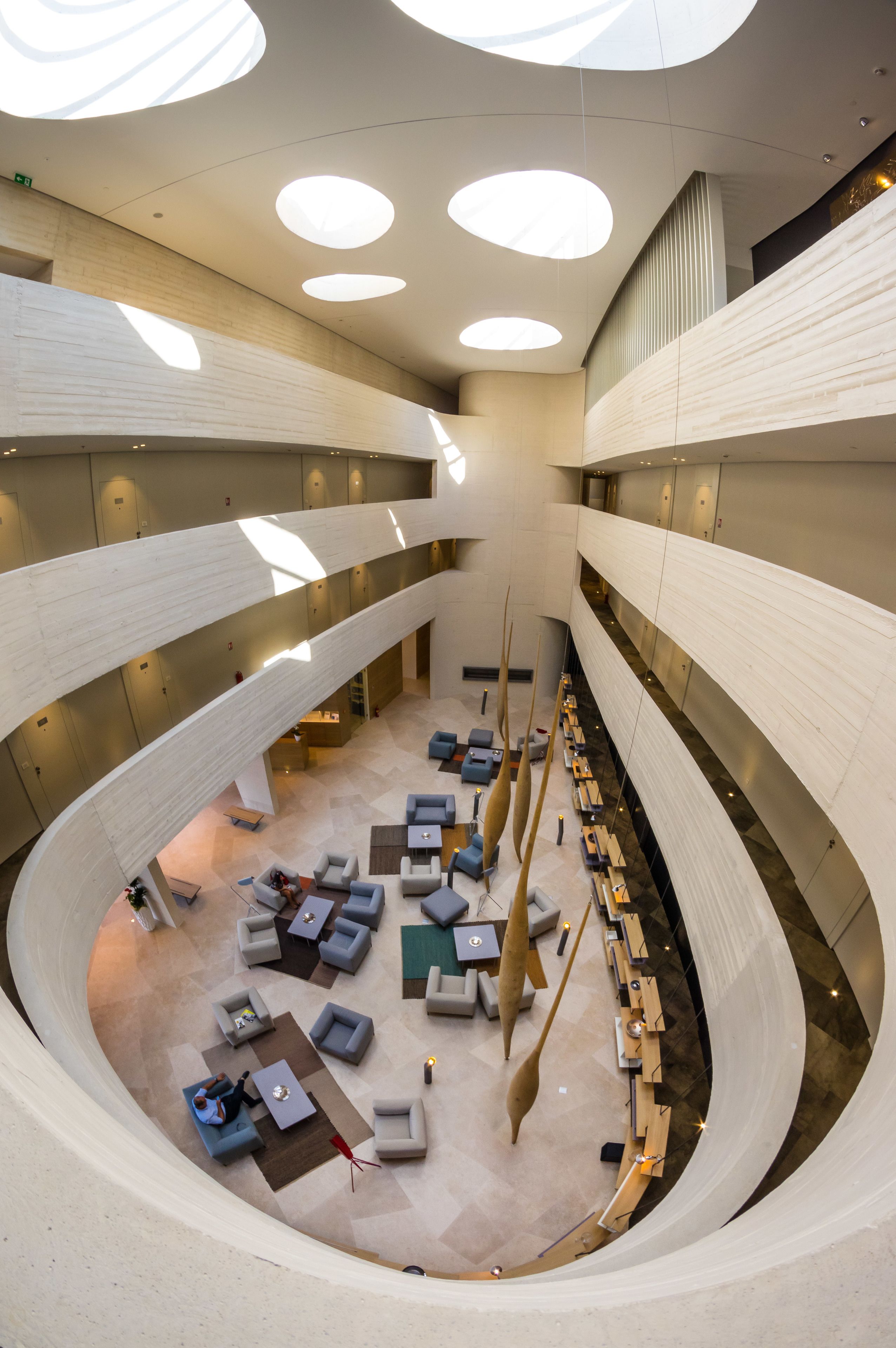 A modern interior with a central open space, multiple levels, and a variety of seating arrangements.