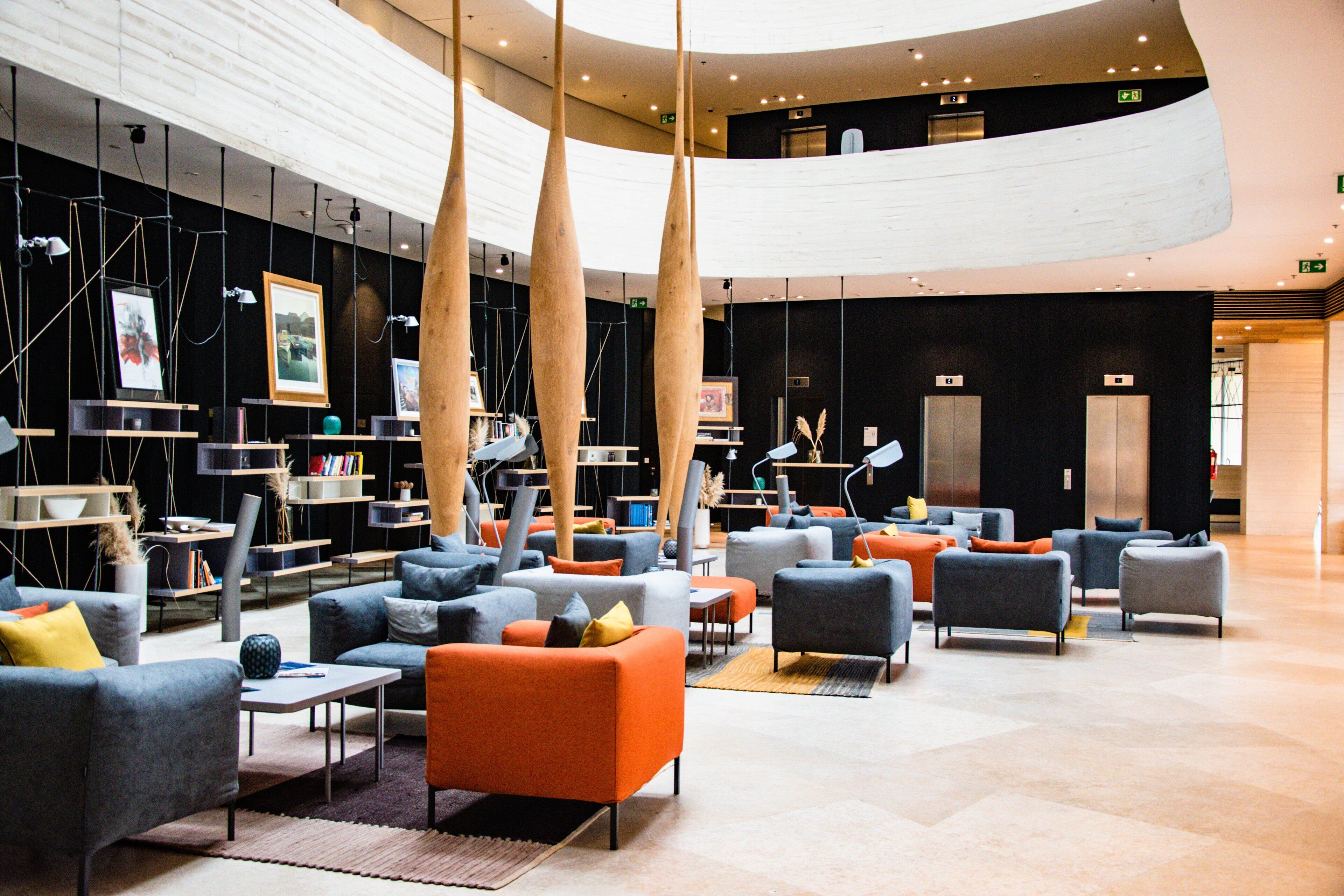 Un hall d’entrée spacieux avec de nombreux espaces de détente, un plafond haut orné de luminaires suspendus et un design moderne.
