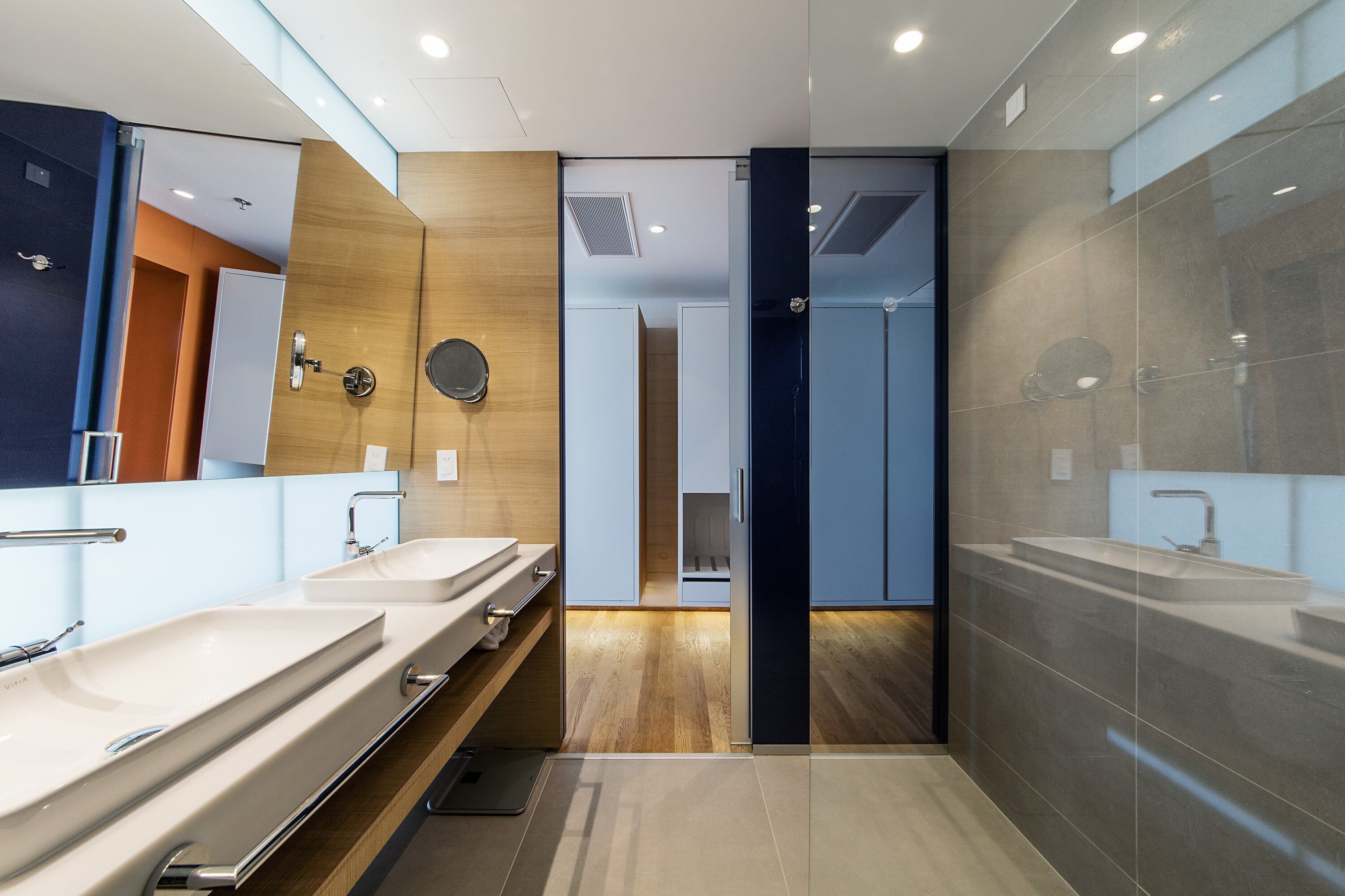 Un baño moderno con dos lavamanos, un espejo y una pared de madera decorativa.