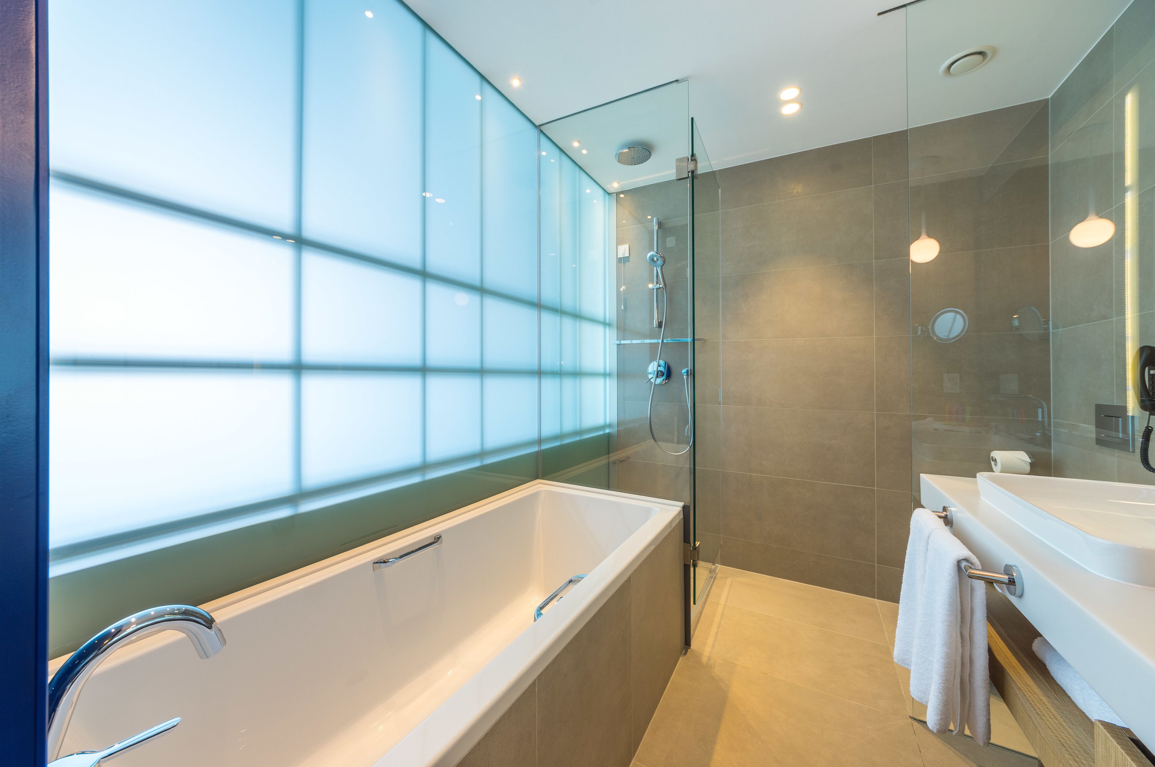 Un baño moderno con dos lavamanos, cabina de ducha con mampara de vidrio y un ventanal amplio.