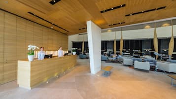 Una moderna zona de recepción con mostrador de madera, área de descanso y un ventanal grande.