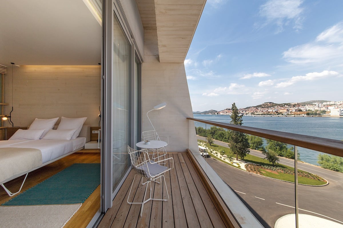 A balcony with a bed, a small table, and a chair.
