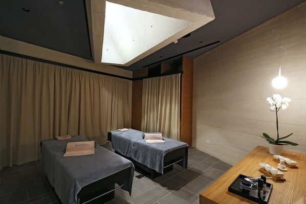 A spa room with two massage tables, a wooden reception desk, and a potted orchid. - D-Resort Šibenik (Sibenik)