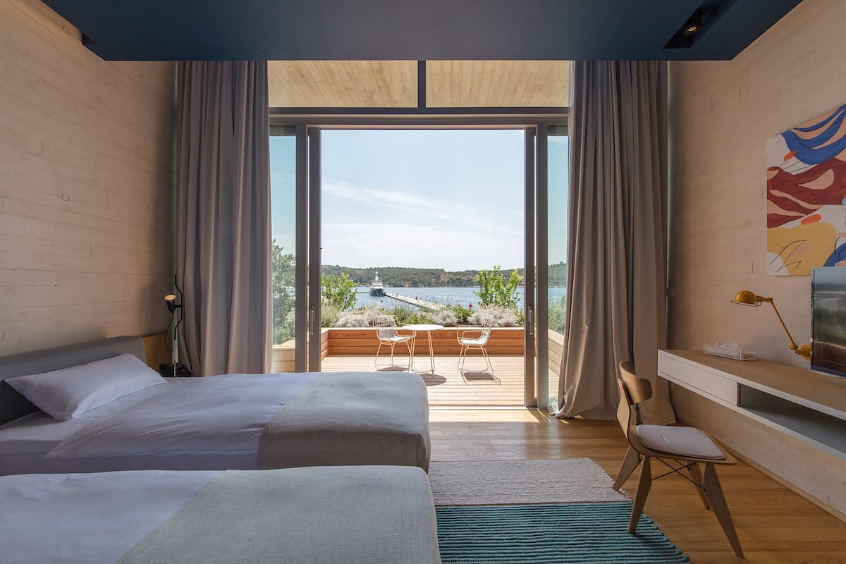 A bedroom with two beds, a desk, and a view of a lake.