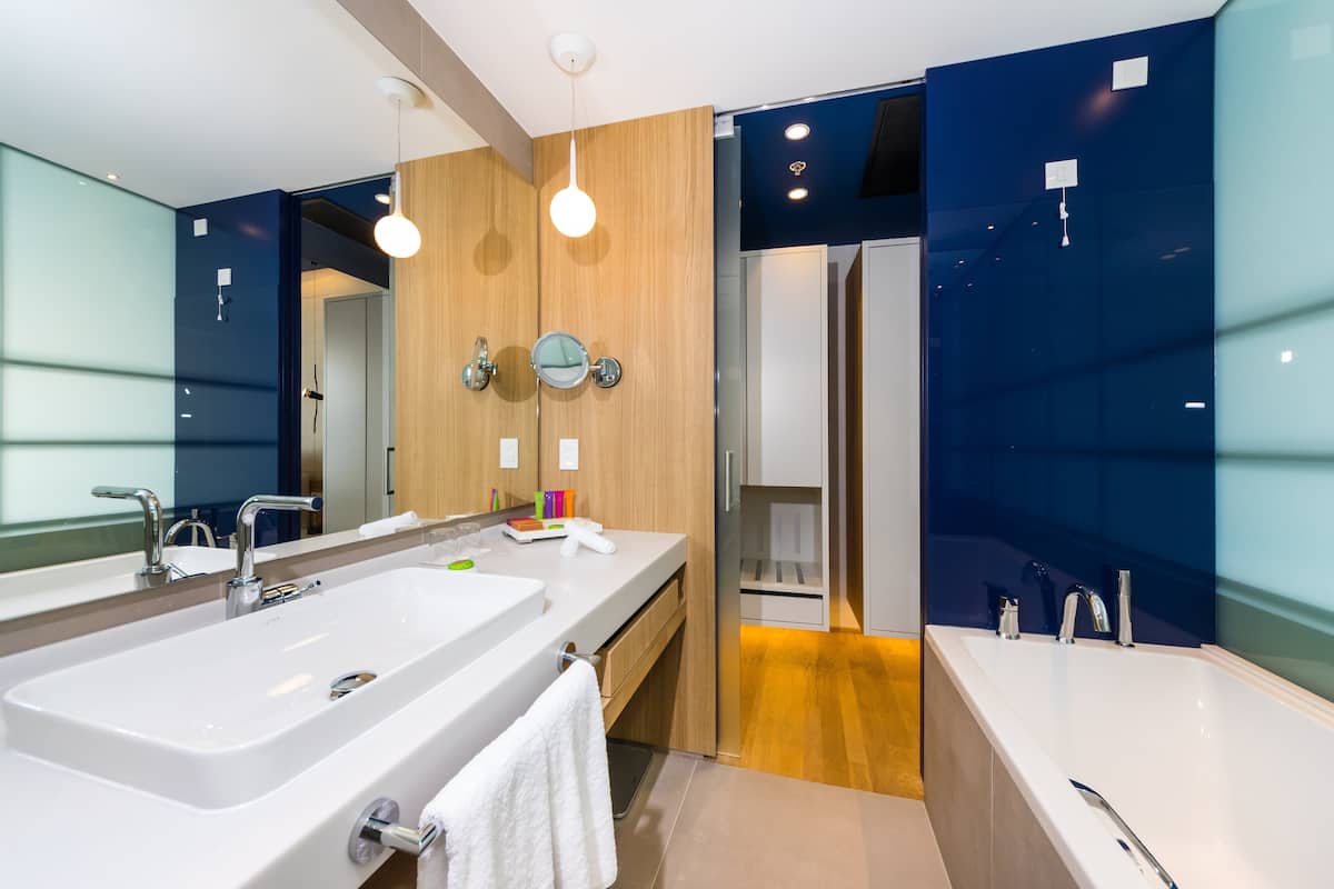 A modern bathroom with a large sink, a mirror, and a bathtub.