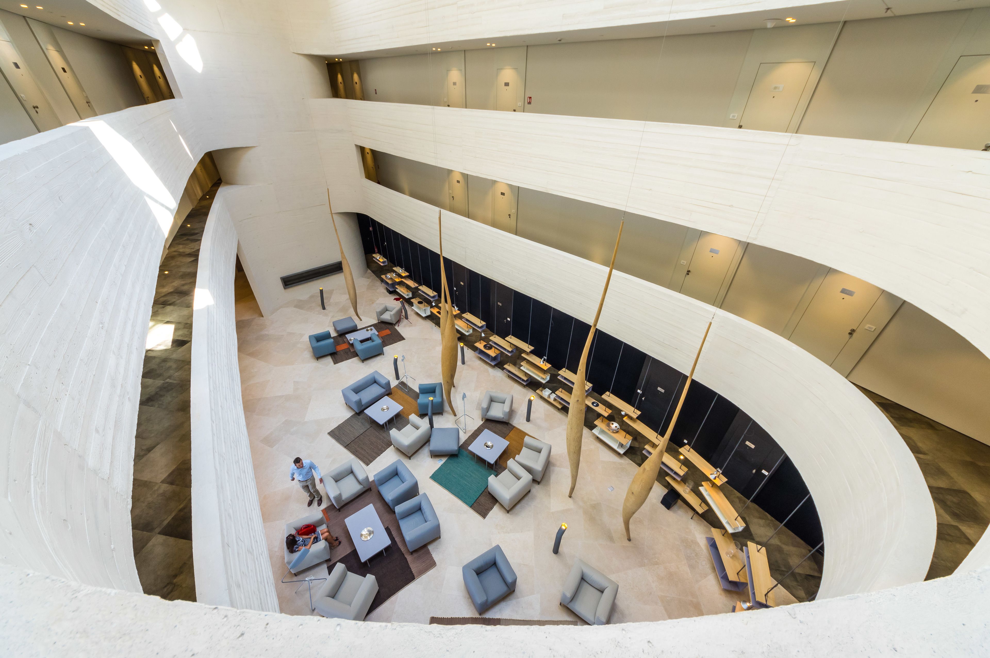 Un vestíbulo amplio con varias zonas de estar, una escalera central y un diseño arquitectónico moderno.