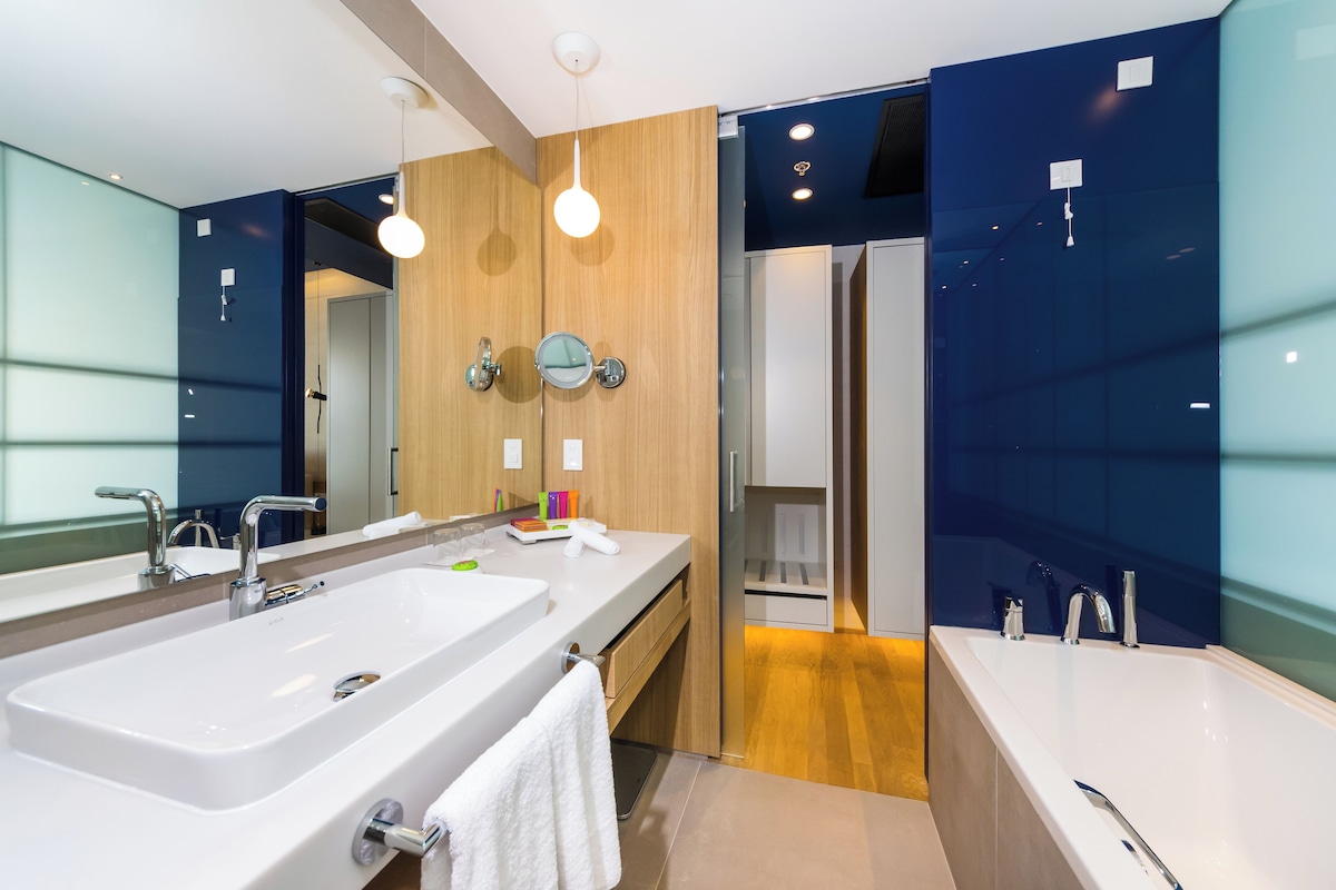 Un baño moderno con un lavamanos grande, espejo y zona de ducha independiente.