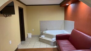 Ein modernes Badezimmer mit einer Badewanne, einem roten Ledersofa und einem kleinen Mülleimer.