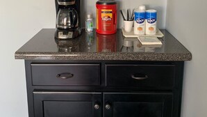 Eine Küchenarbeitsplatte mit Kaffeemaschine, Folgers-Kaffee und zwei NJOY-Nachfüllbehältern.