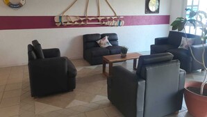 Een zithoek met zwarte banken, een houten tafel en een aan de muur bevestigde touwschommel.