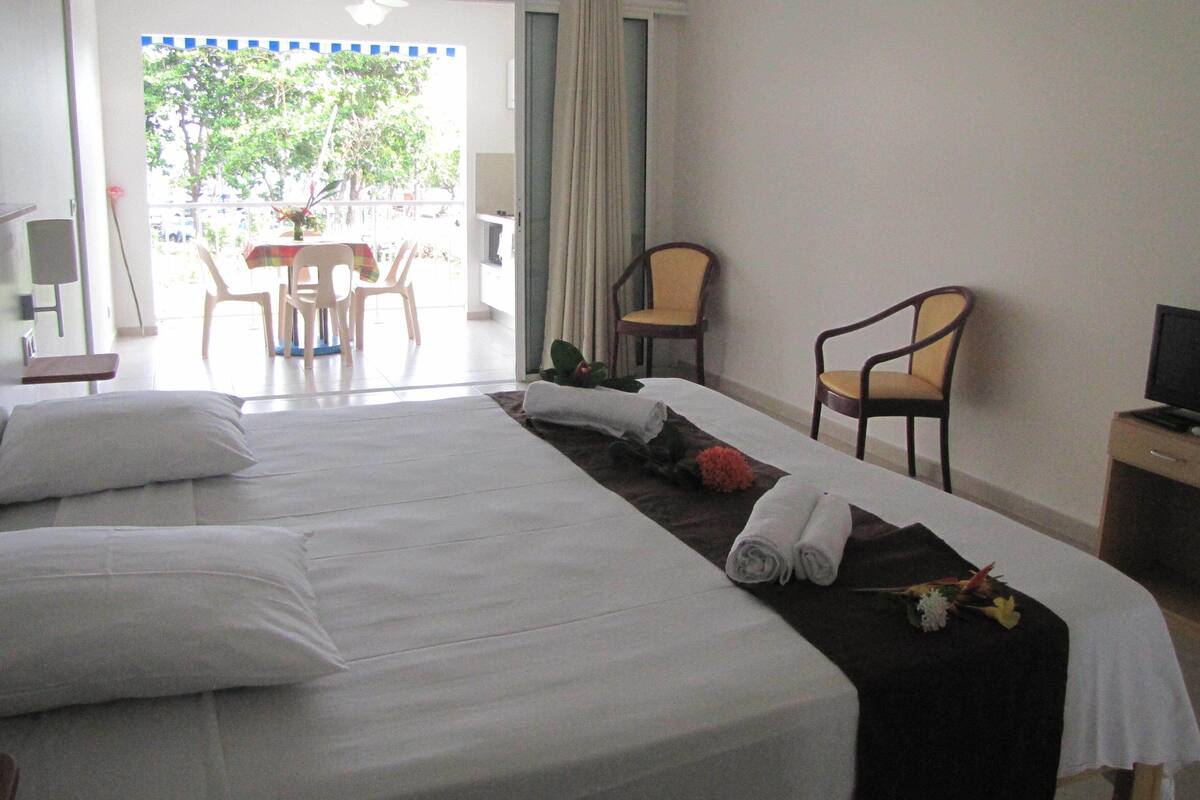 A hotel room with two beds, a desk with a computer, a chair, and a view of the outside.
