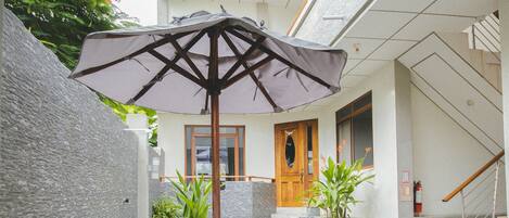 An outdoor patio with a round table and chairs, a wooden door, and potted plants.