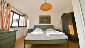 A bedroom with a bed, a dresser, a painting, and a window with curtains. - Haus Wartenberg (Salzburg)