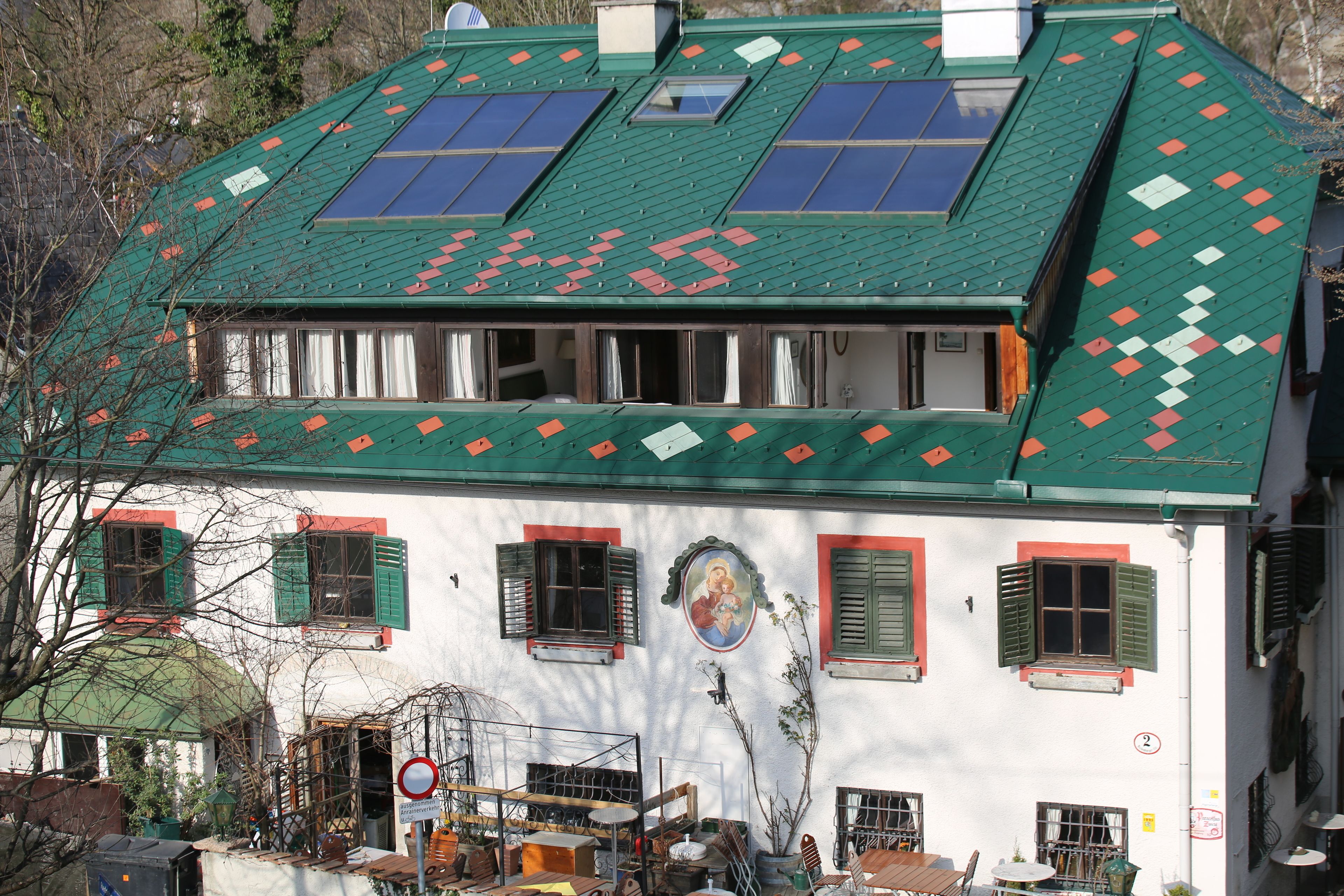 A building with a green roof, multiple windows, and a visible sign with the number 2.