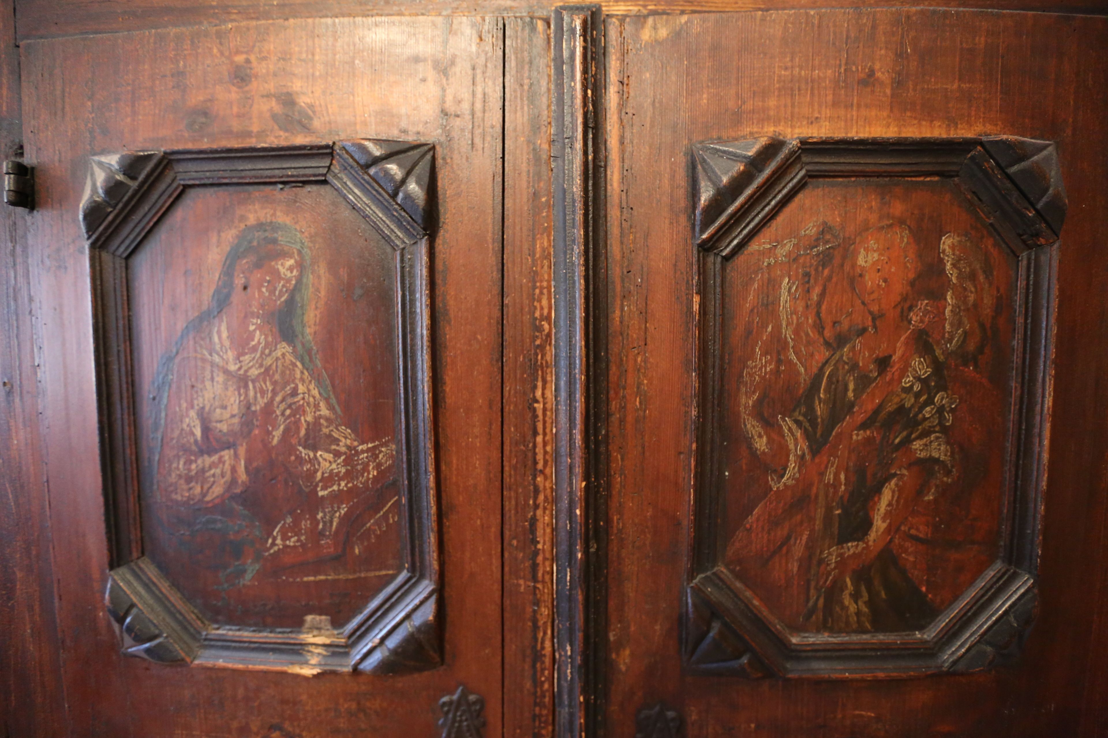 A wooden door with two framed religious paintings.