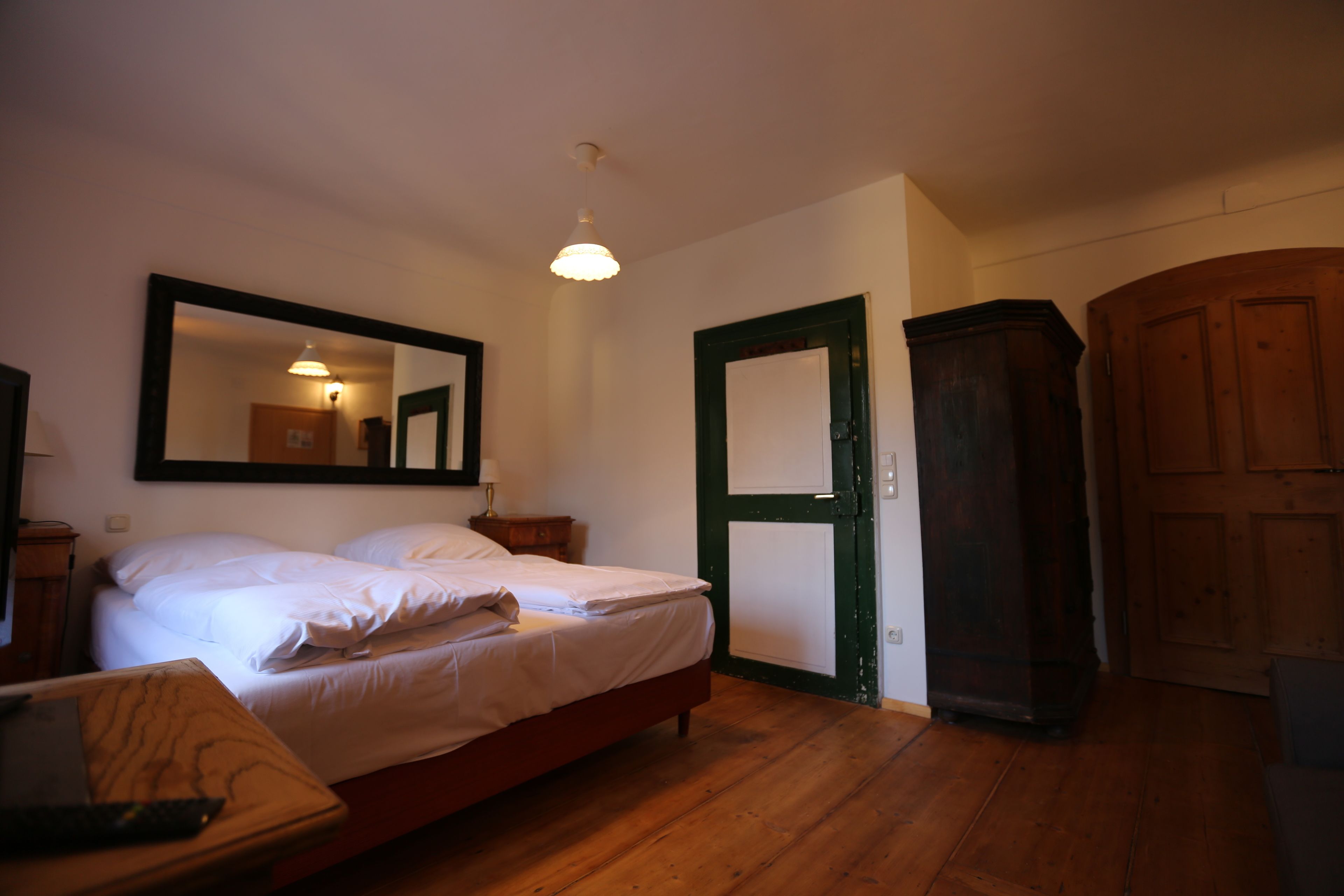 Un dormitorio con cama, armario de madera y un espejo en la pared.