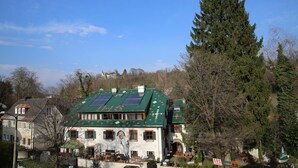 A building with a green roof, solar panels, and a traditional architectural style. - Haus Wartenberg (Salzburg)