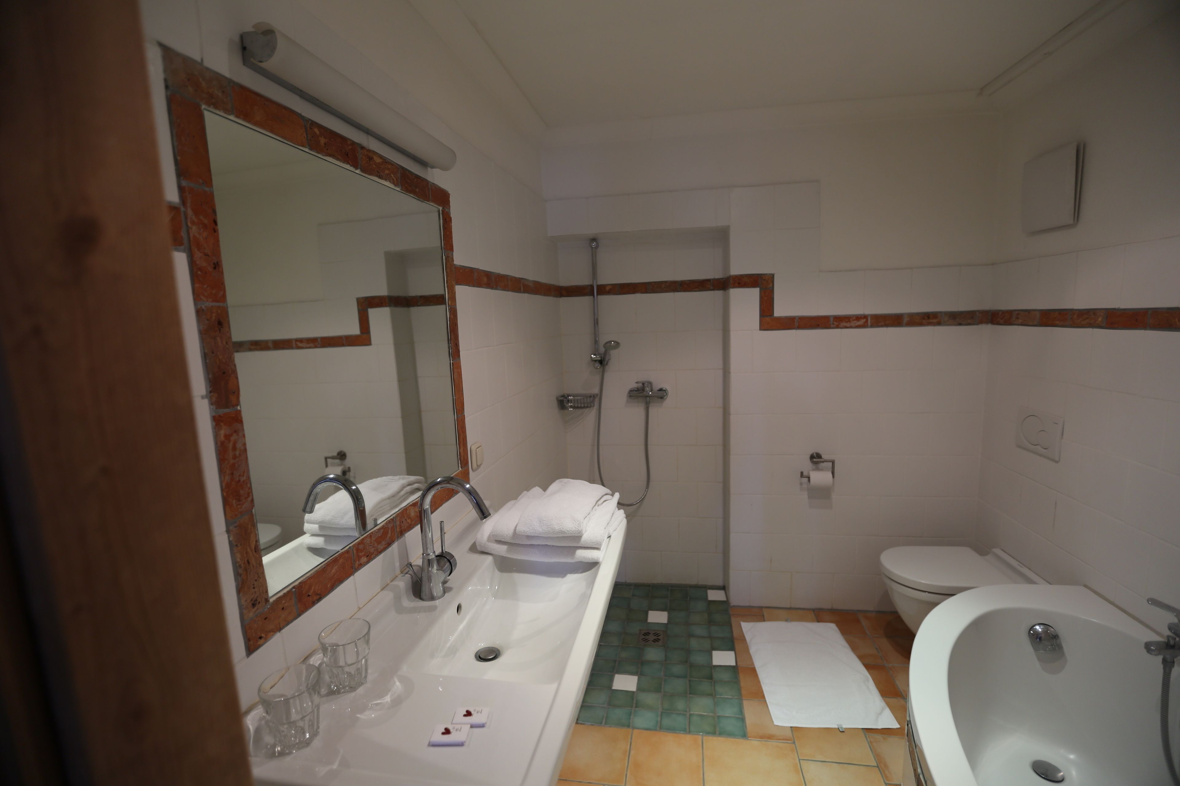 Un baño con lavabo, espejo, ducha e inodoro.