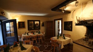 A dining area with multiple tables set for meals, wooden chairs, and a stone floor. - Haus Wartenberg (Salzburg)