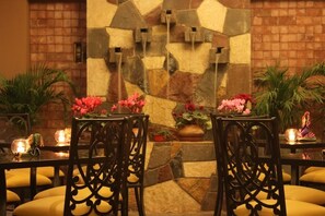 A restaurant with stone walls, two chairs with floral centerpieces, and candle-lit tables. - La Casa de Don Ignacio (Cusco)