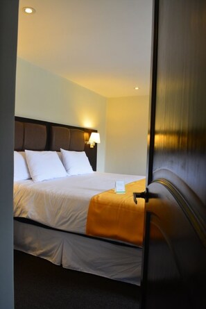 A hotel room with a bed, a nightstand, a lamp, and a door. - La Casa de Don Ignacio (Cusco)
