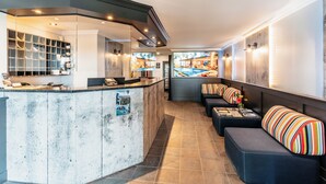 A reception area with a counter, seating area, and a large screen displaying a pool scene. - Hotel Motel Le Quiet (Lac-Megantic)