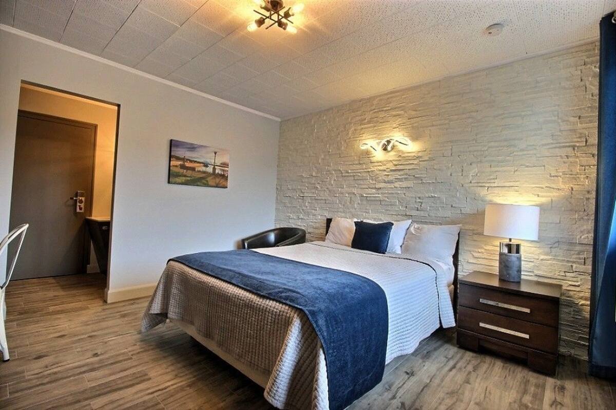 A bedroom with a bed, a nightstand, a chair, and a door.