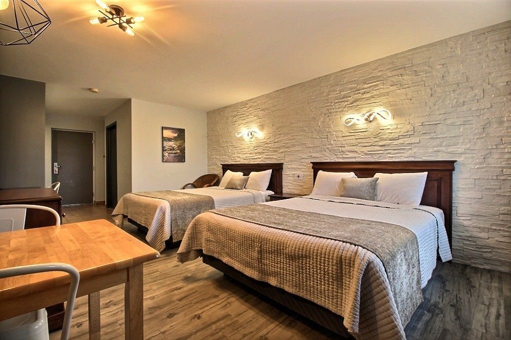 Habitació d'hotel amb dos llits, una taula de fusta i una paret de pedra.