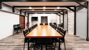 A conference room with a long wooden table, black chairs, and a TV mounted on the wall. - Hotel Motel Le Quiet (Lac-Megantic)