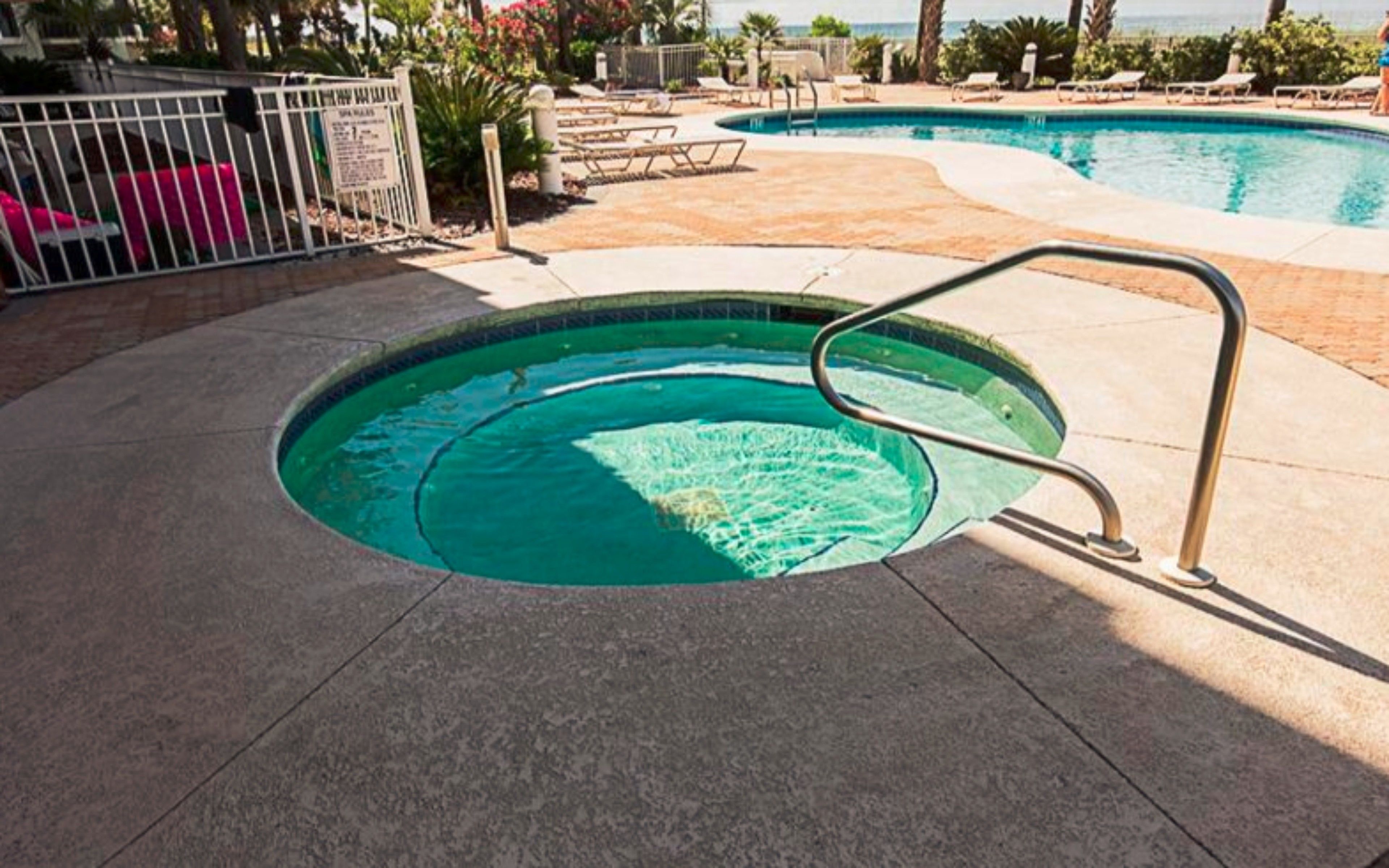 A swimming pool with a metal ladder, surrounded by lounge chairs and a tiled deck.