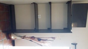 Un coin de pièce avec un mur recouvert de carreaux, un banc en bois sombre et un balai appuyé contre le mur.