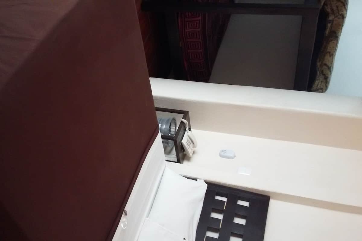 Een kamer met een bed, een nachtkastje en een wandradiator.