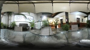Un hall d’hôtel doté d’une piscine à fond de verre, de palmiers et d’une enseigne indiquant « Hôtel Punta Punta ».