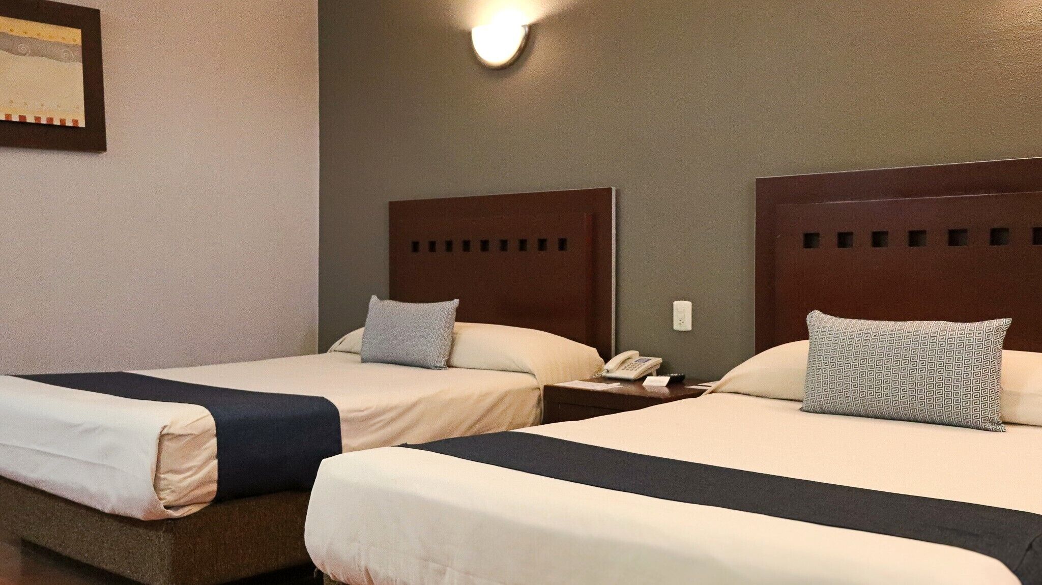 Une chambre d’hôtel avec deux lits, chacun doté d’une tête de lit, de tables de chevet et d’oreillers.