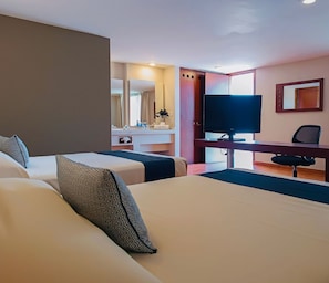 Ein Hotelzimmer mit zwei Betten, einem Schreibtisch, einem Fernseher und einem Spiegel.
