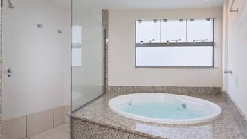 A modern bathroom with a glass shower enclosure, a freestanding bathtub, and a window with a view of the sky.