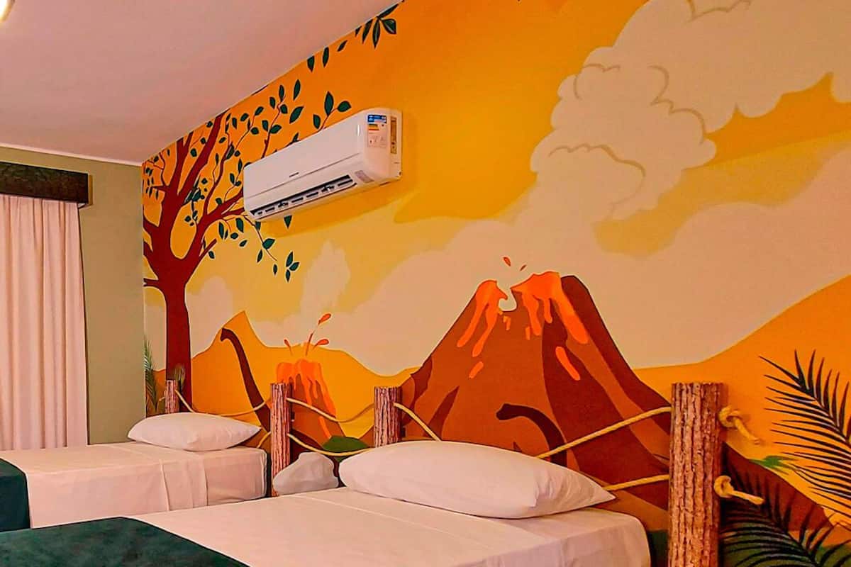 Ein Hotelzimmer mit zwei Betten, einem Wandgemälde eines Vulkans und einer Klimaanlage.