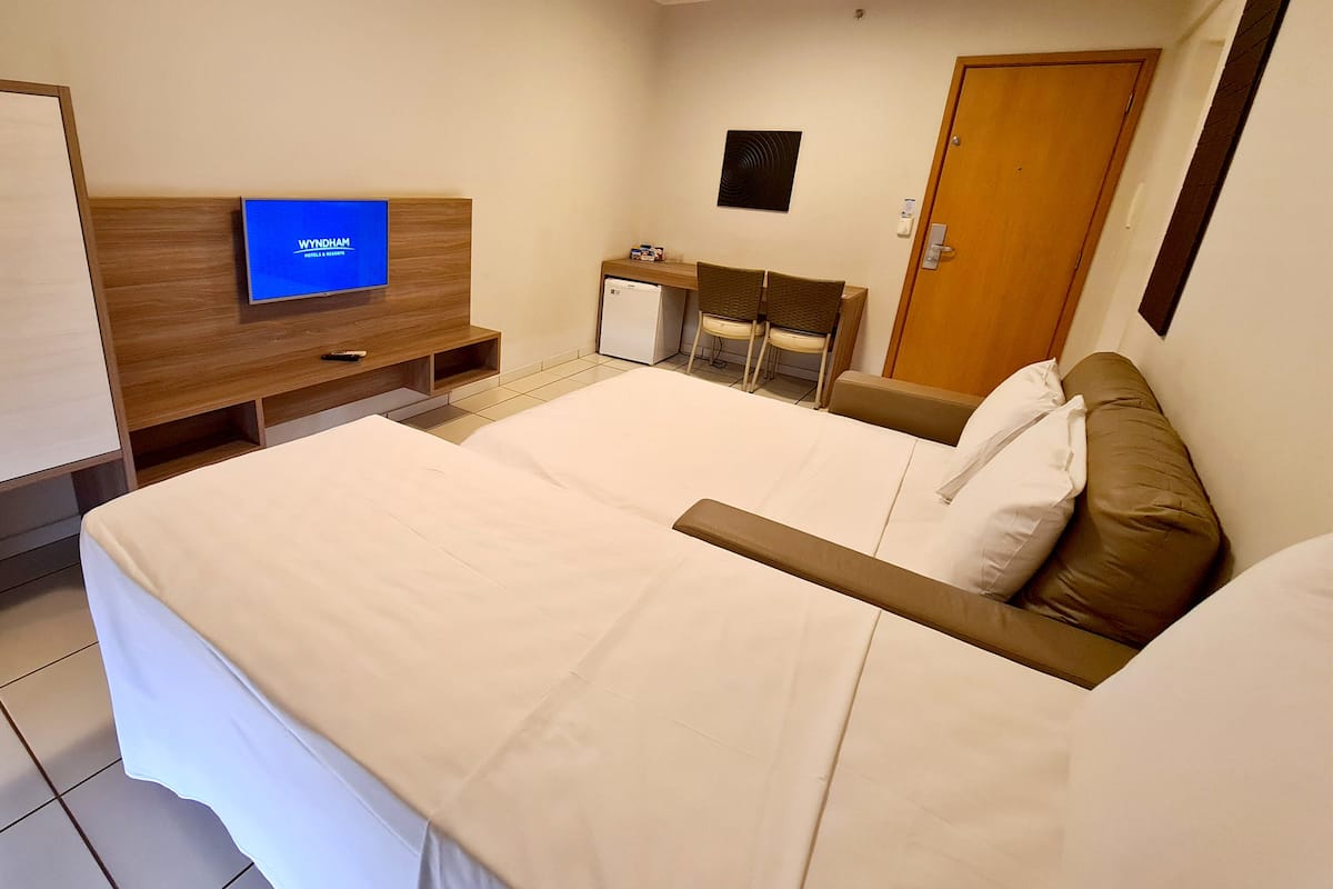Ein Hotelzimmer mit Bett, Schreibtisch, Stuhl, Fernseher und einer Tür.