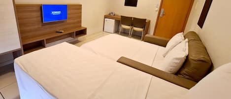 Et hotelværelse med seng, skrivebord, stol, fjernsyn og dør.
