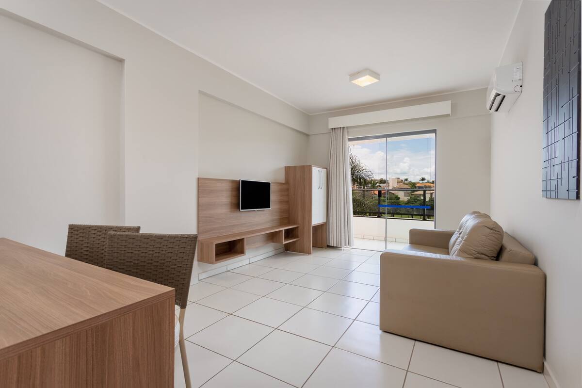 Ein modernes Wohnzimmer mit Flachbildfernseher, Holzmöbeln, einer Couch und einem Balkon mit Blick.