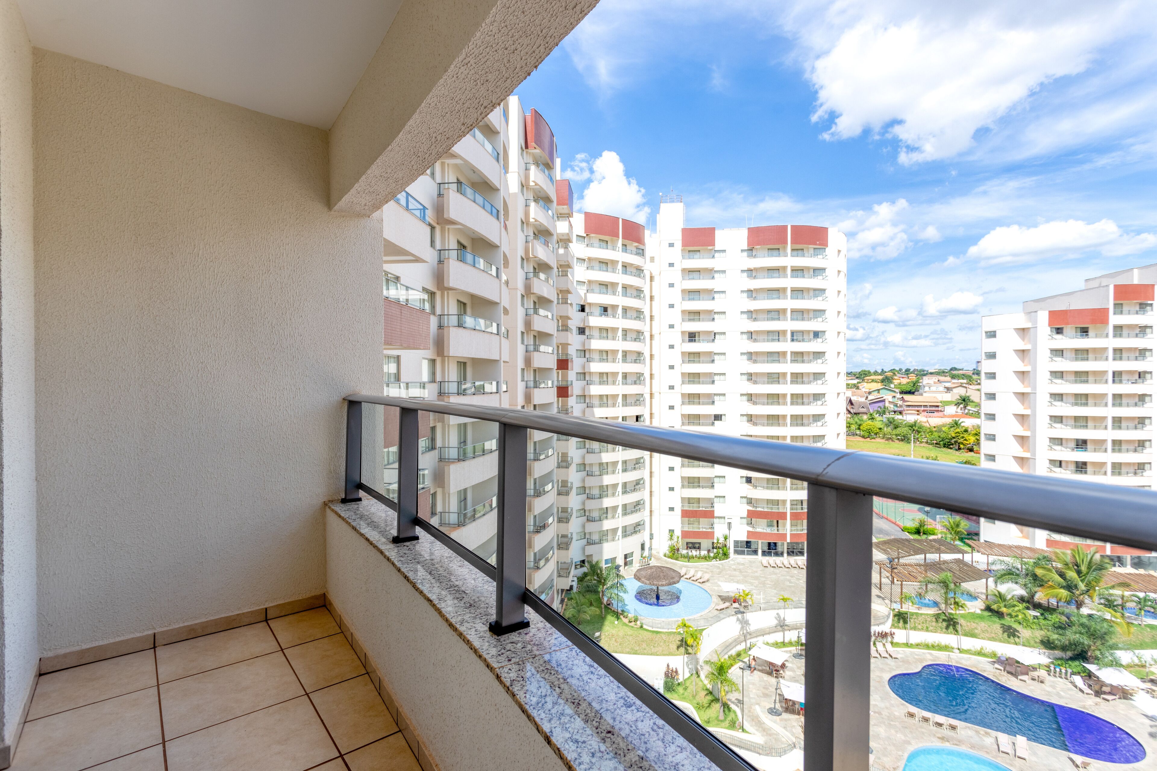 A balcony with a view of a swimming pool and high-rise buildings.