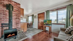 A living room with a fireplace, a sofa, a TV, and a dining area with chairs and a table. - Walker River Lodge (Bridgeport)