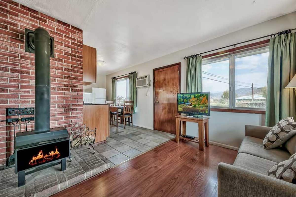 Una sala de estar con chimenea, un sofá, un televisor y una zona de comedor con sillas y una mesa.