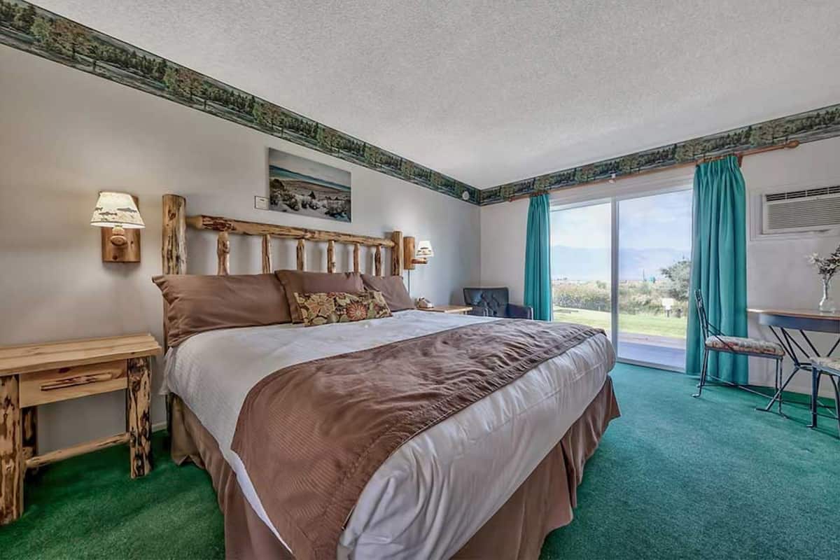 Un dormitorio con una cama grande, un escritorio y una silla. Se ve una ventana con vistas al exterior.