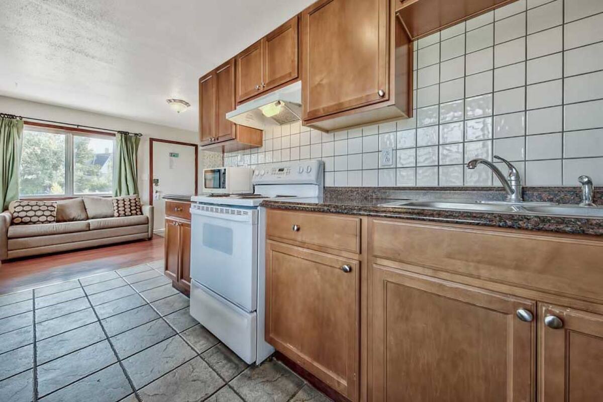 Una cocina con armarios de madera, estufa blanca y salpicadero de azulejos.