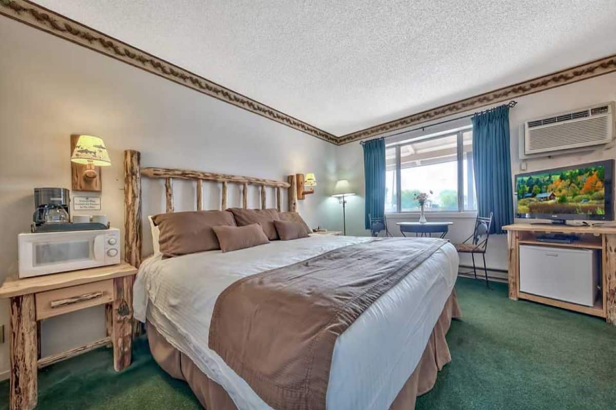 Habitación de hotel con una cama grande, un escritorio con microondas, una silla y un televisor.