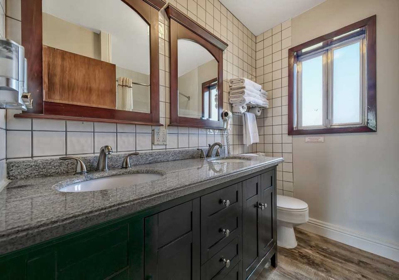 Une salle de bain avec un meuble-lavabo à deux vasques, un grand miroir et une fenêtre.