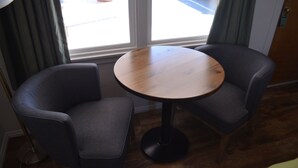 Une pièce avec une table ronde en bois et deux chaises grises recouvertes de tissu.
