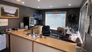 Un comptoir d’accueil équipé d’un ordinateur, d’une chaise, d’une lampe de bureau et d’une fenêtre donnant sur un paysage agréable.