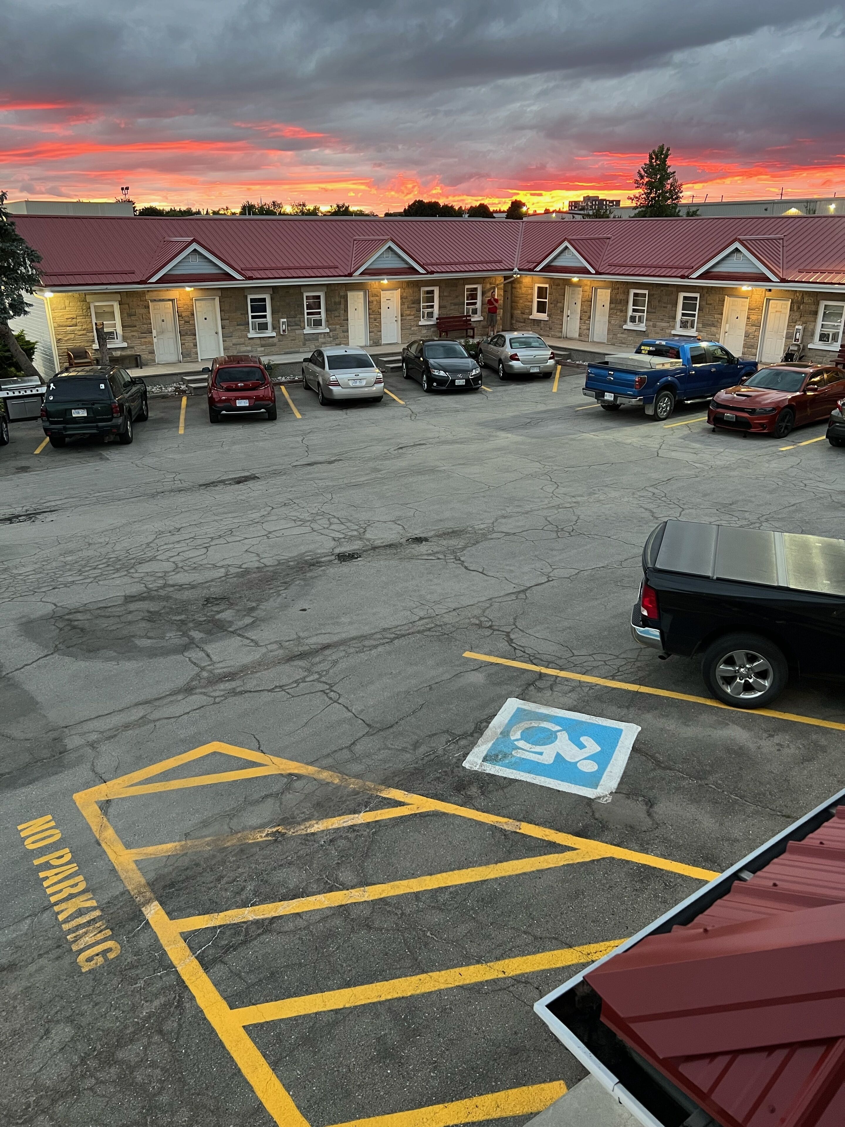 A parking lot with several cars, a handicapped parking sign, and a building with a red roof in the background.
